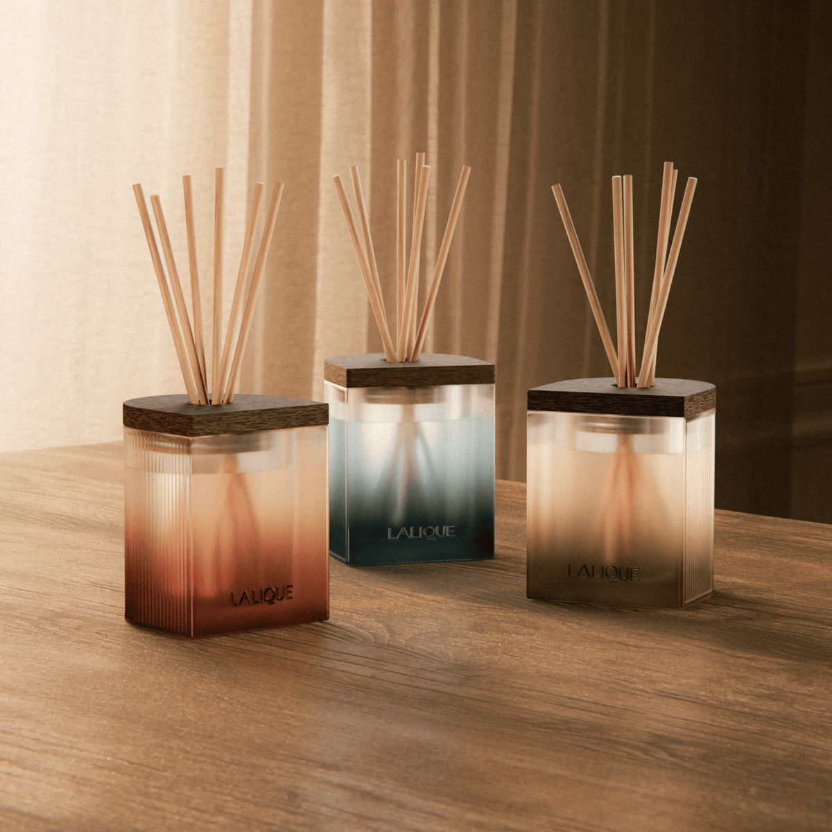 Three diffusers with wooden sticks on a wooden surface, featuring the Lalique brand.